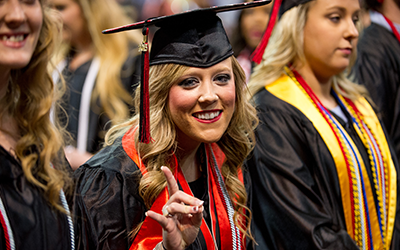 Student at graduation making the redwolf hand sign
