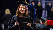 A graduate holding up their diploma