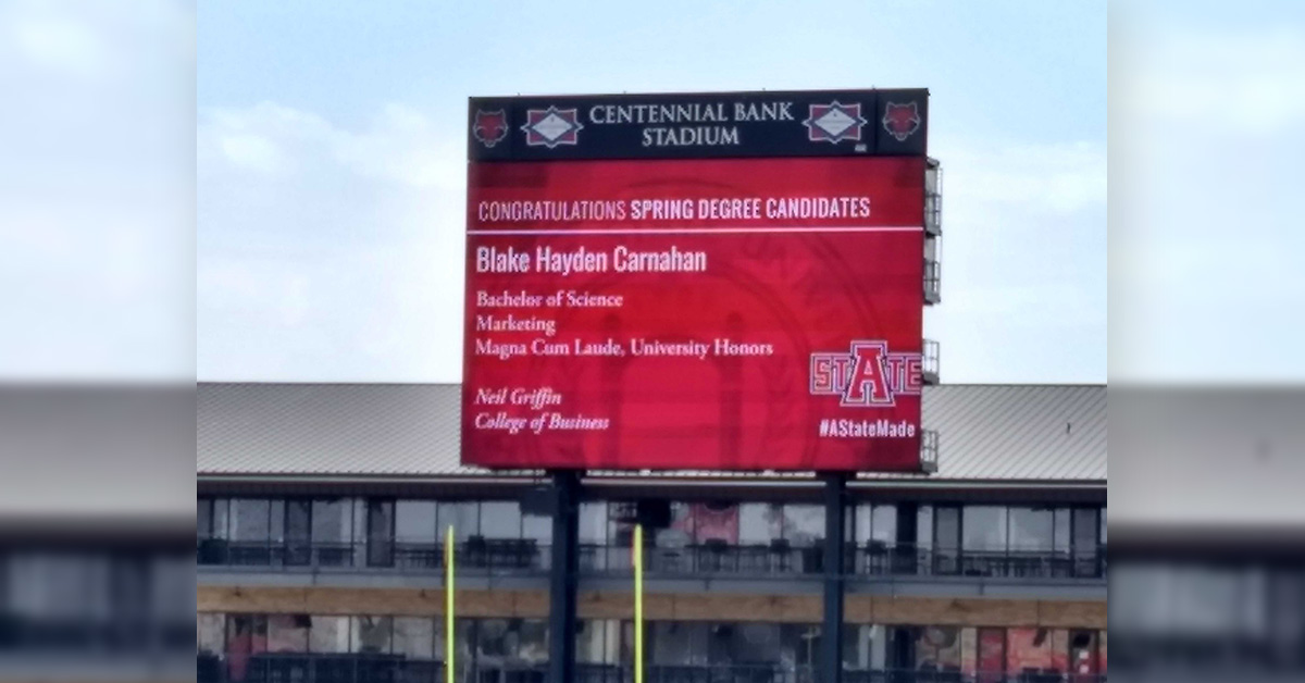 A graduate's information appears on the video board