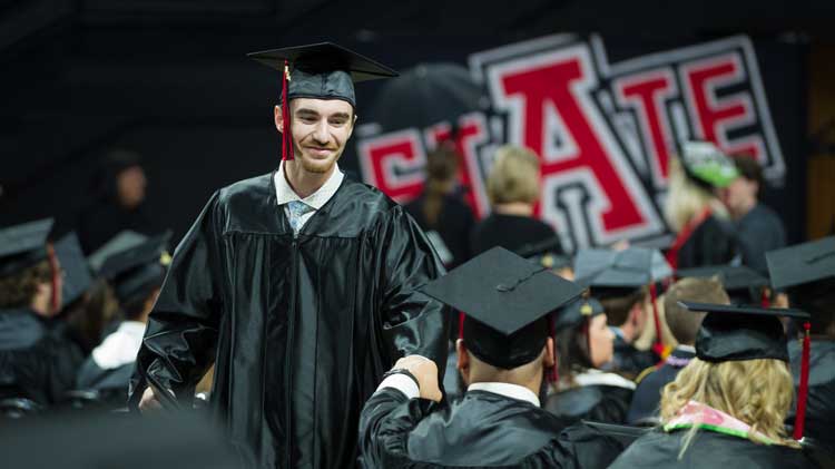 A student fist bumping a professor at commencement