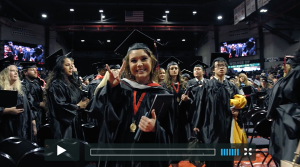 A student giving Wolves Up at commencement.