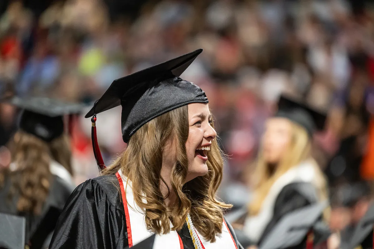 A graduate smiles and laughs during a recent commencement ceremony