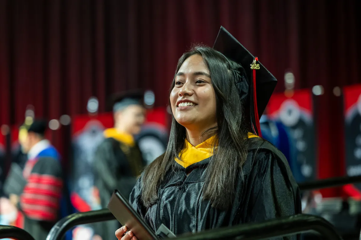 A graduate looks to the crowd proudly after crossing the commencement stage