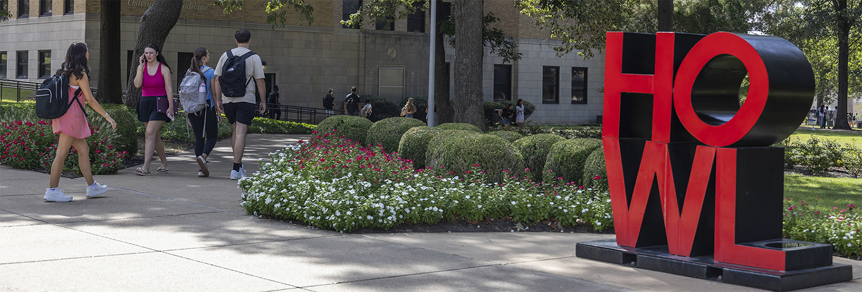 students walking outside by the HOWL statue