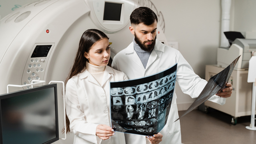 2 people in white coats looking at x-ray image