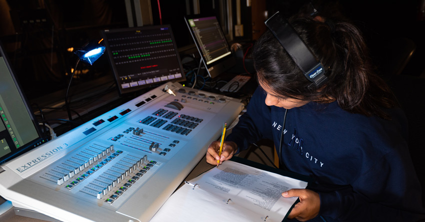 A student taking lighting notes in the booth