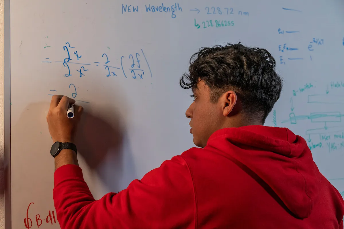 A student does a calculation on a white board