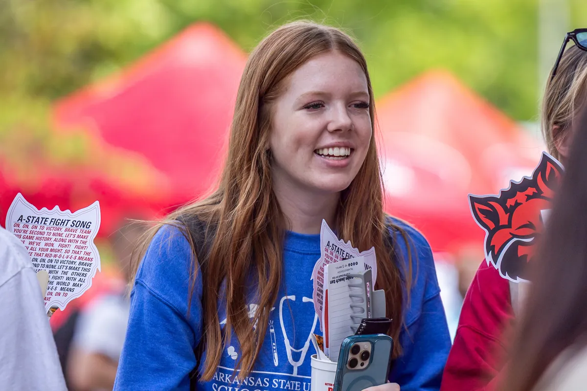 A student smiles while visiting an information booth during welcome week
