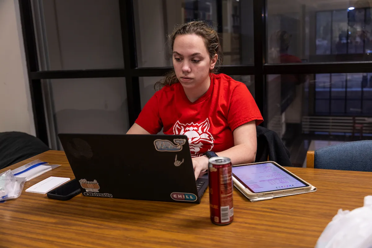 A student works on a laptop in the library.
