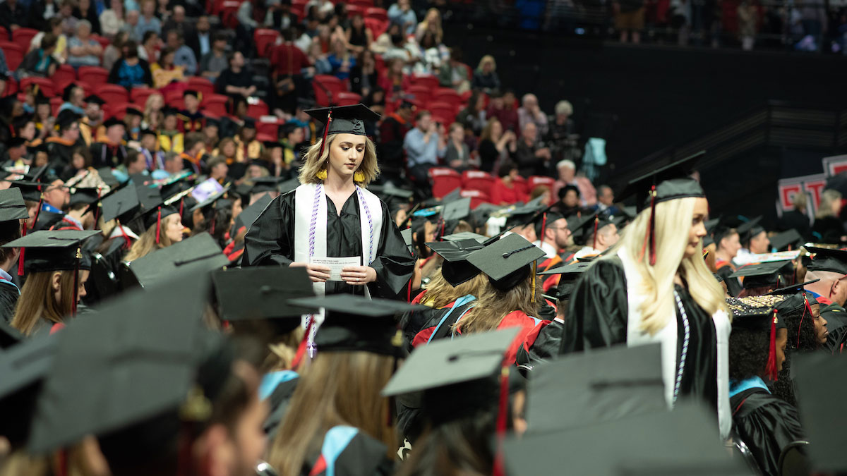 A graduate walks back to her seat at a recent indoors commencement ceremony.