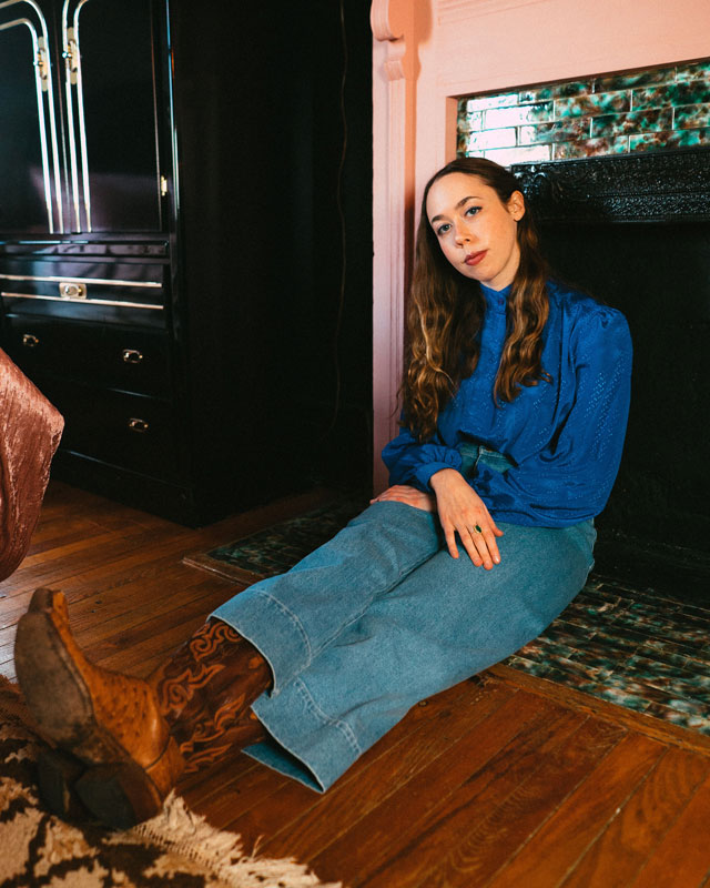 Sarah Jarosz sits in front of a fireplace