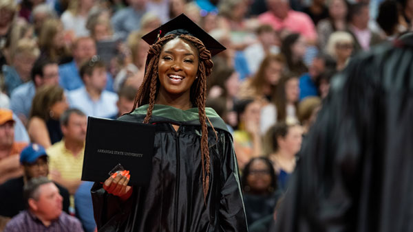 A graduate shows off her diploma at a 2019 commencement ceremony