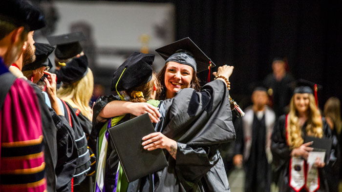 Graduates hug after Summer Commencement 2023