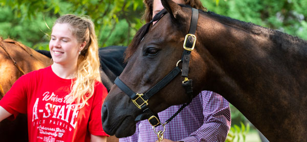 Students leading a horse at the equine center.