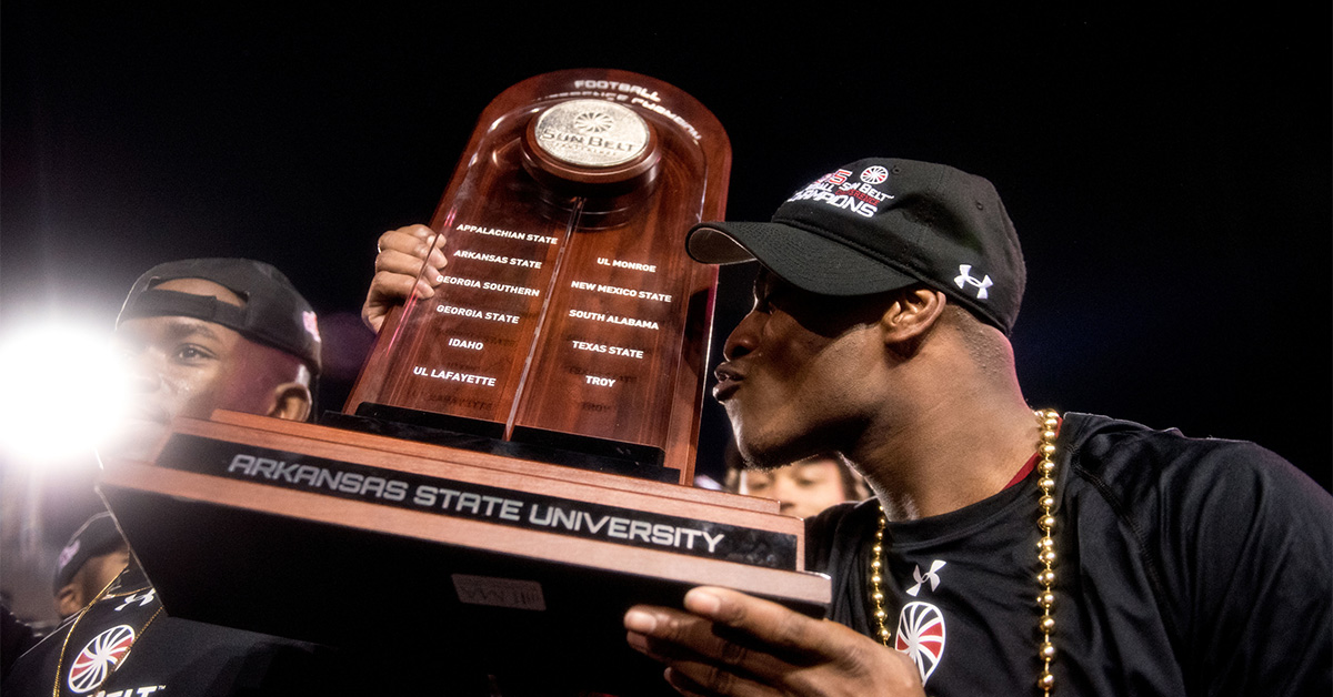 A-State player holding the Sun Belt Trophy