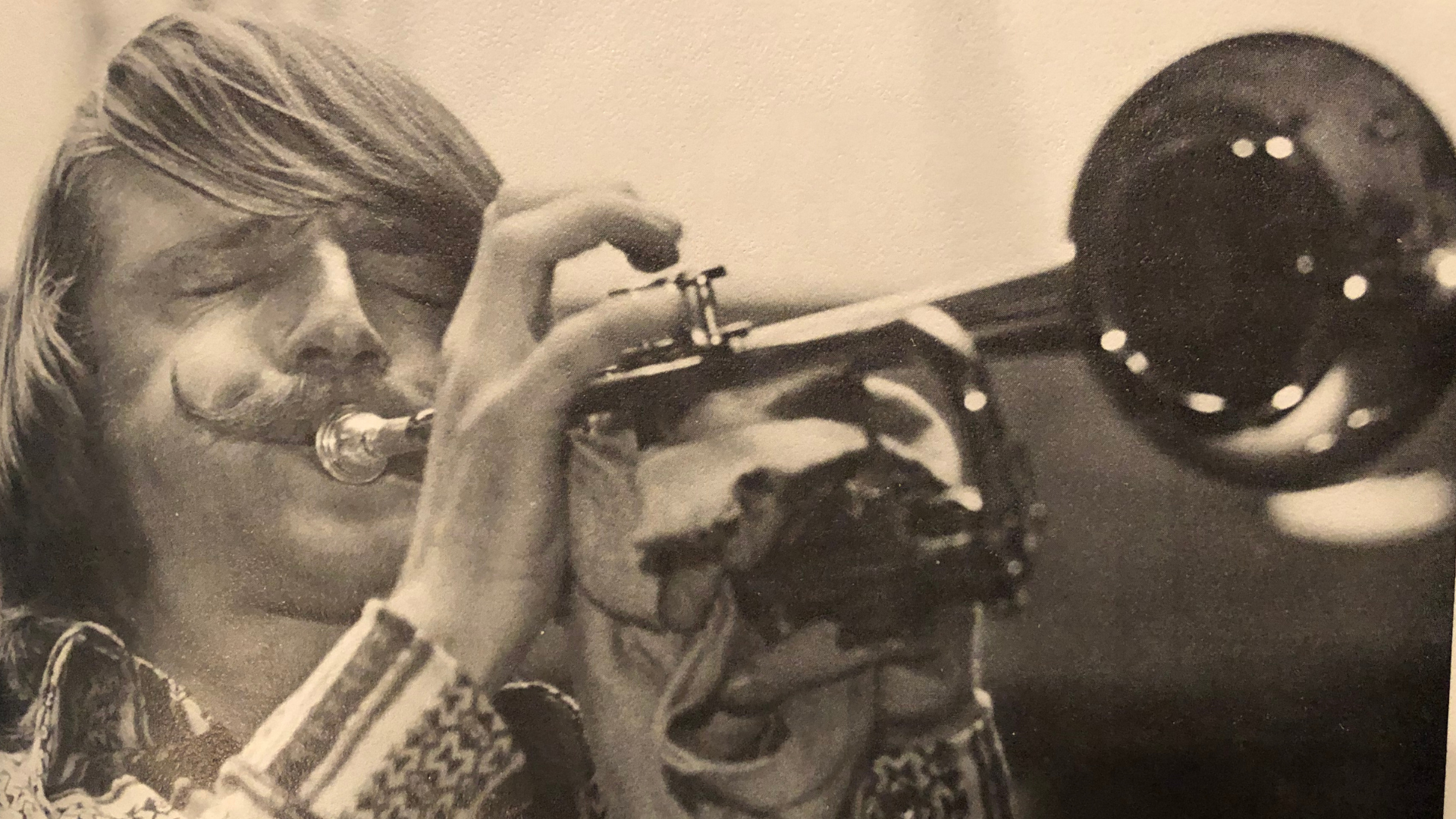 Photograph of a trumpet student from the 1970s.  He is playing the trumpet, eyes closed with a handlebar mustache.