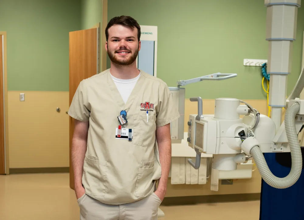 A-State radiography student standing by an xray machine at NEA Hospital