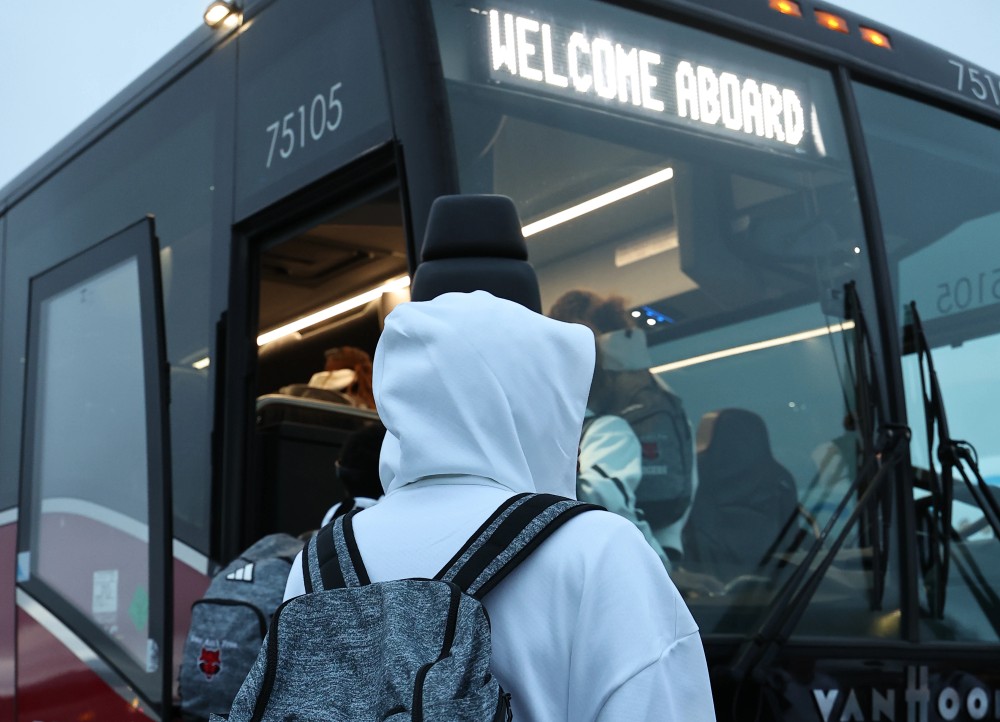 A student looks towards the front of a bus before boarding
