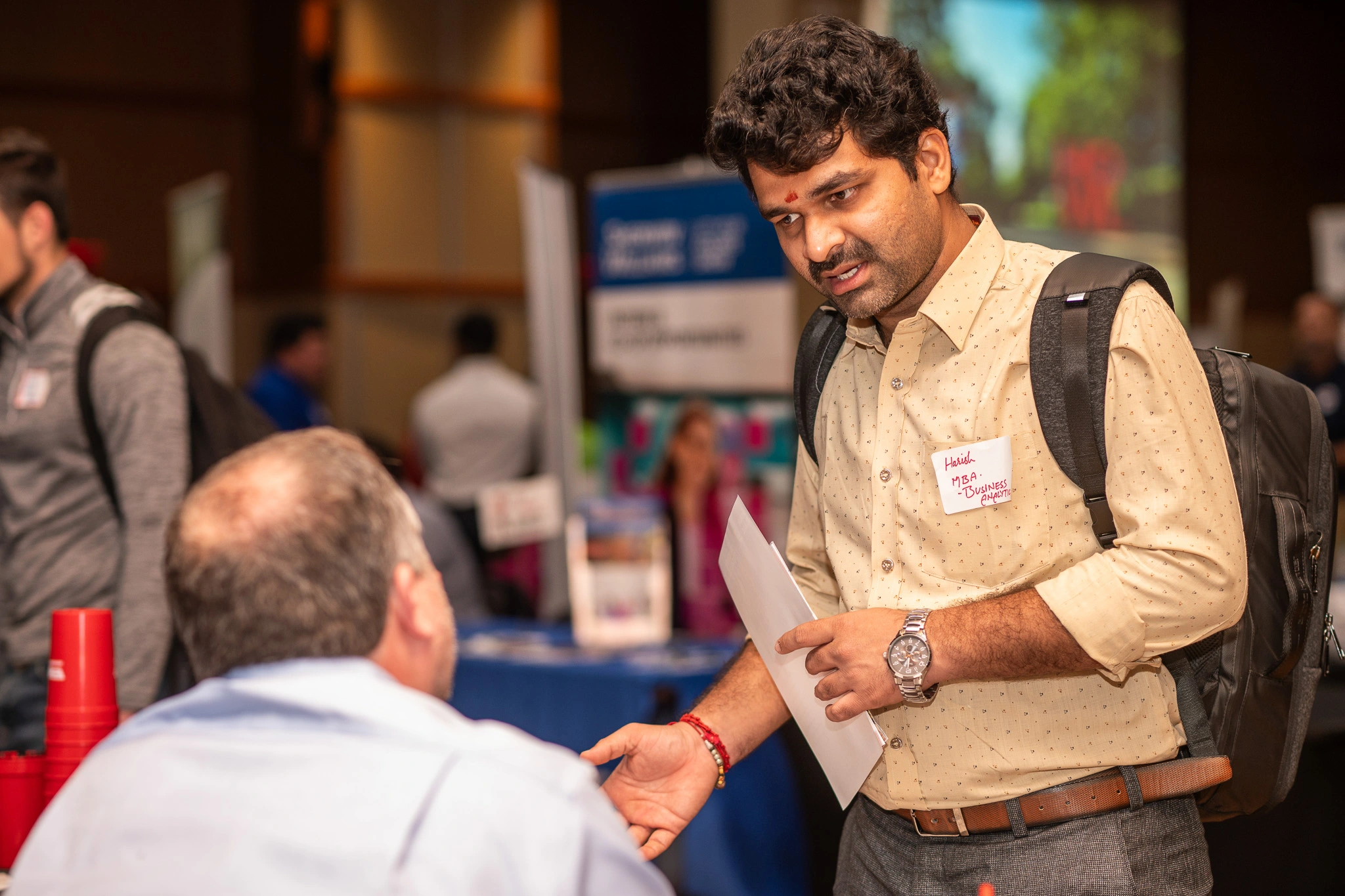 Student speaks with an employer at an Arkansas State career fair while holding a résumé.