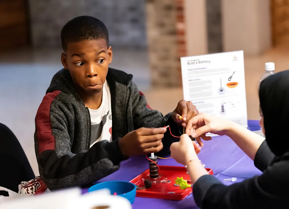 a-state electrical engineering at a STEM event with a kid making a battery