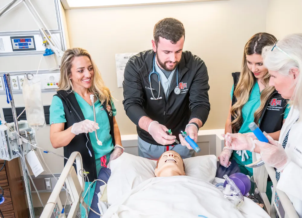 Nurse Anesthesia students in lab with tubes and a dummy patient.