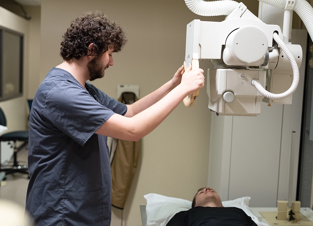 Radiography student using X-Ray machine on another student.