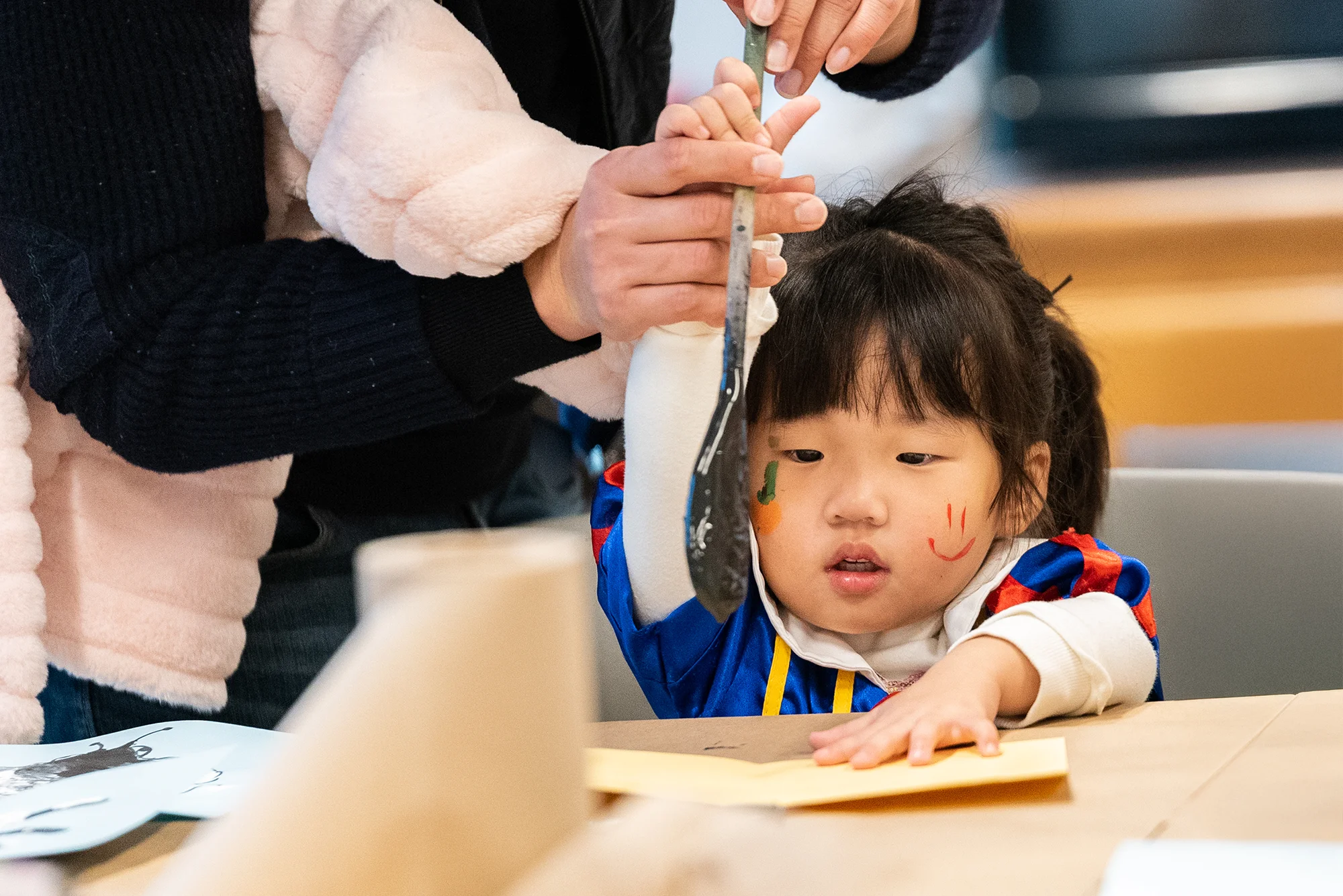 Child painting with smiley face painted on cheek