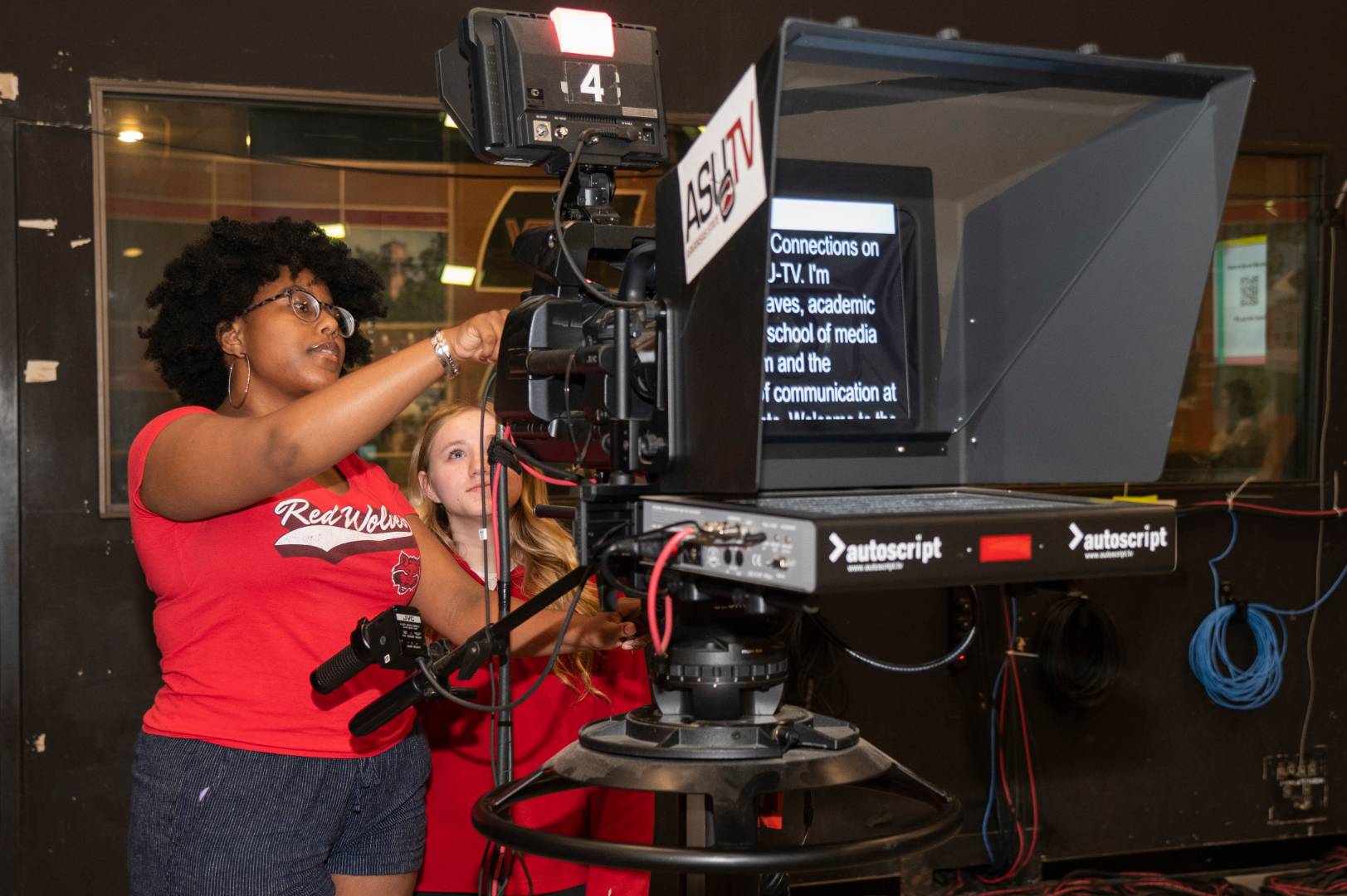 A student being taught how to operate a camera in the newsroom.