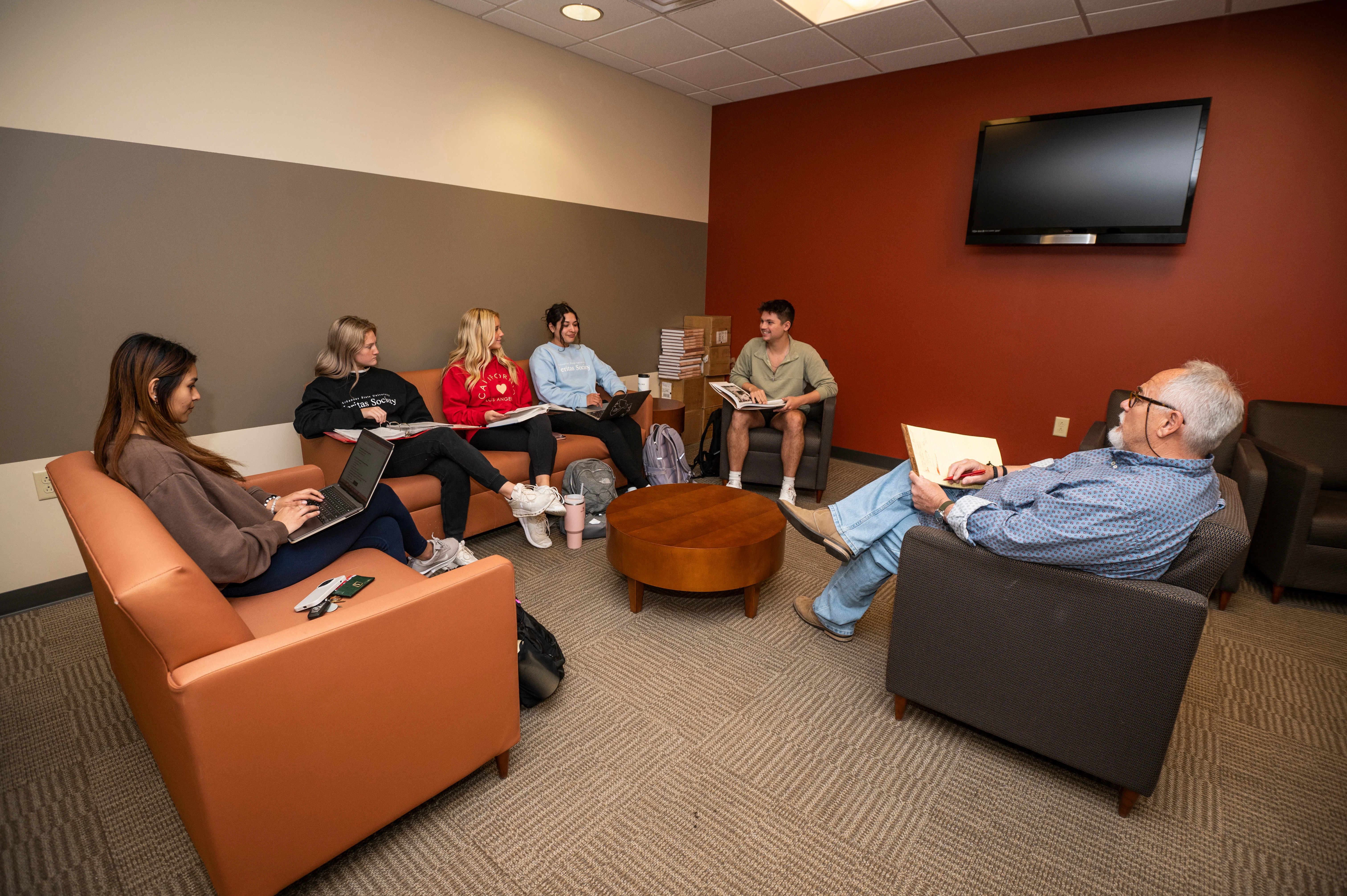 Banking students and teacher having class in banking lounge on couches and chairs.