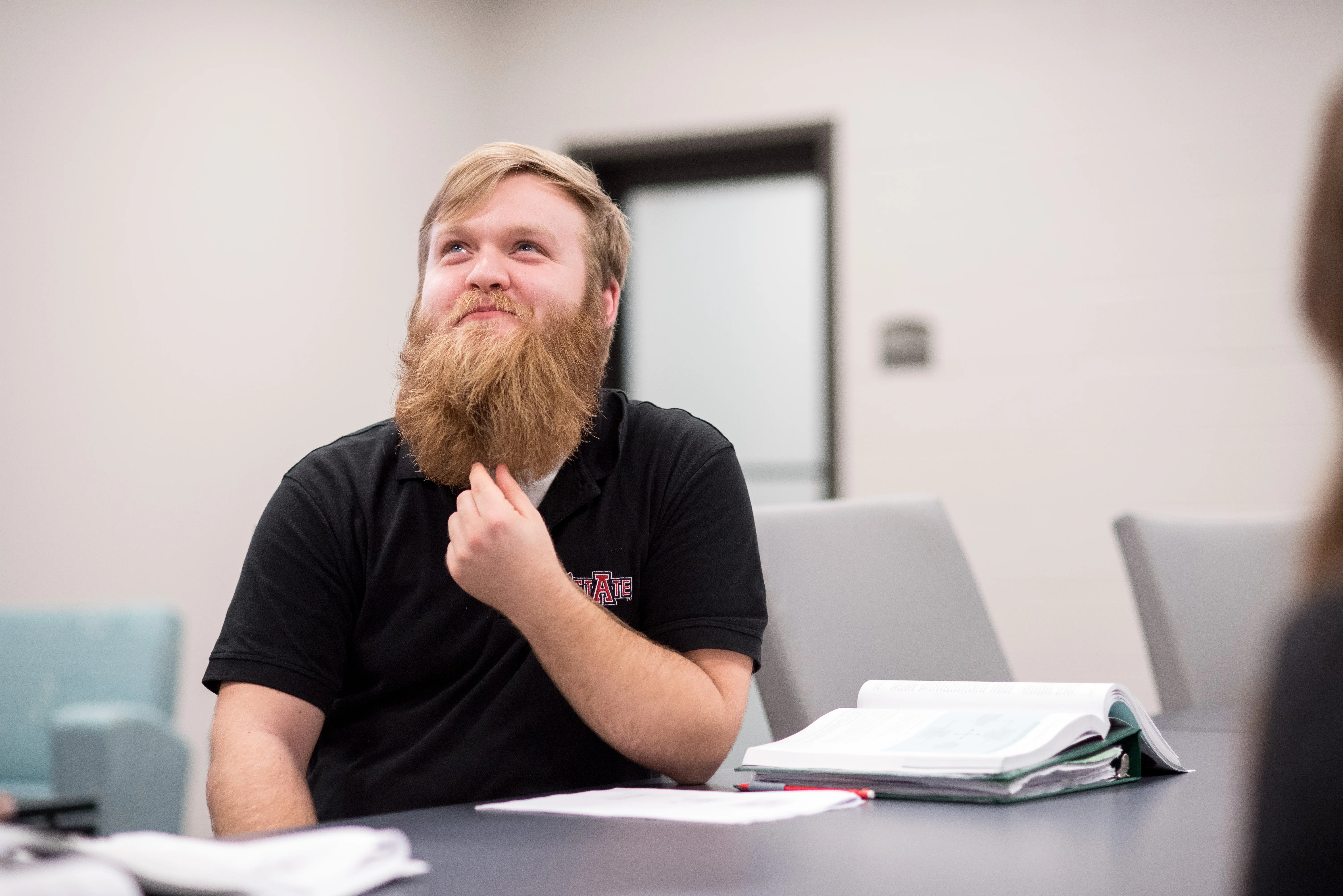 A student stroking his beard while thinking.