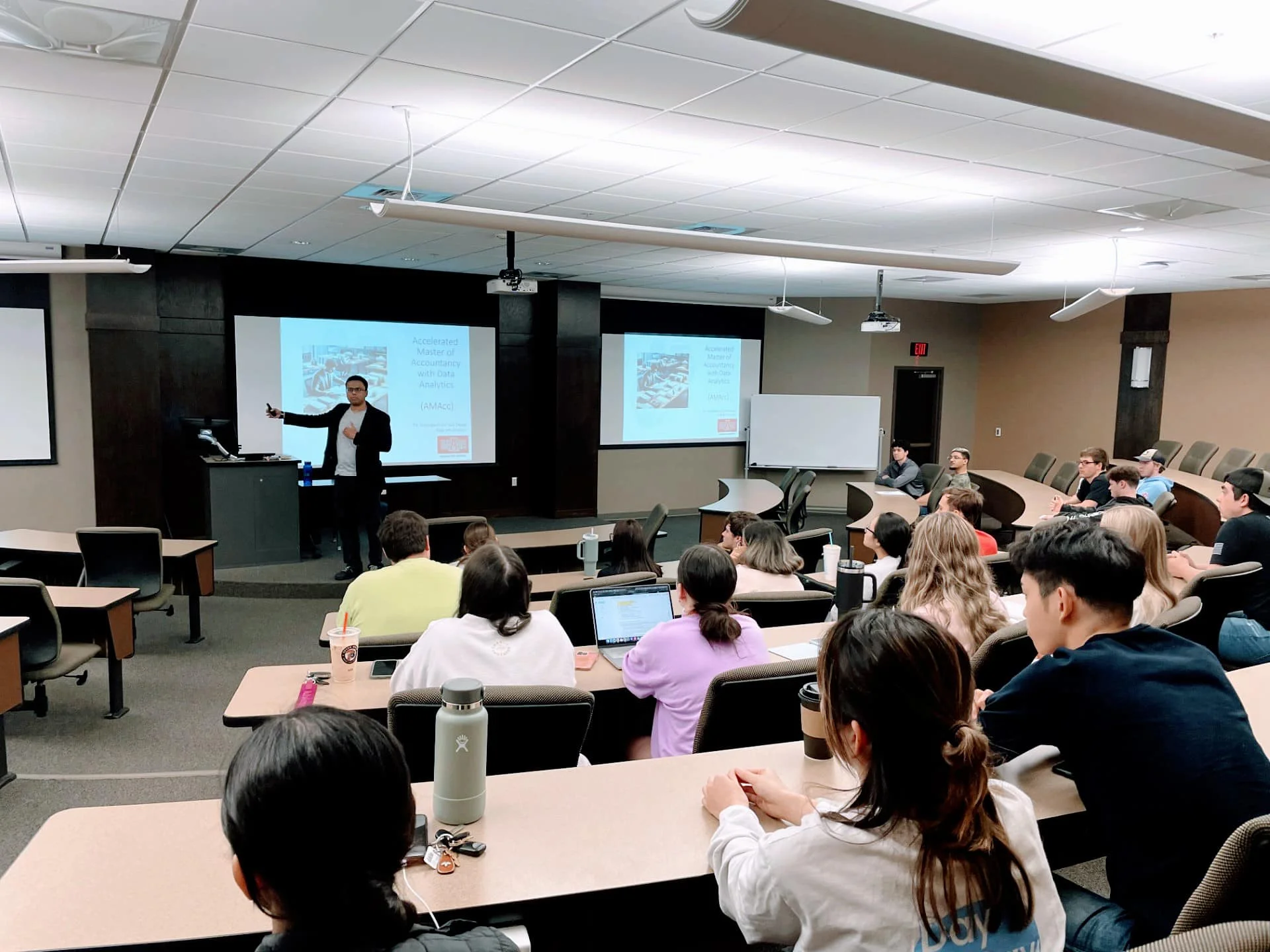 AState students in business class with teacher explaining accounting formulas.