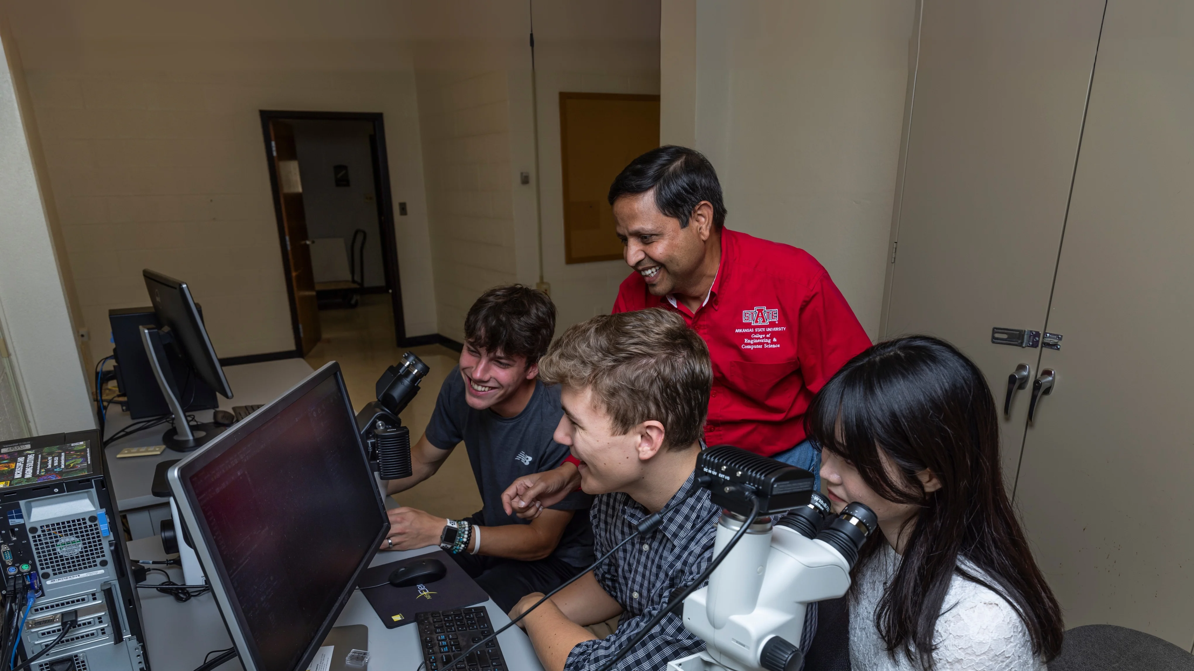 A-State student and professor going over lesson in front of class while they point at the projector.