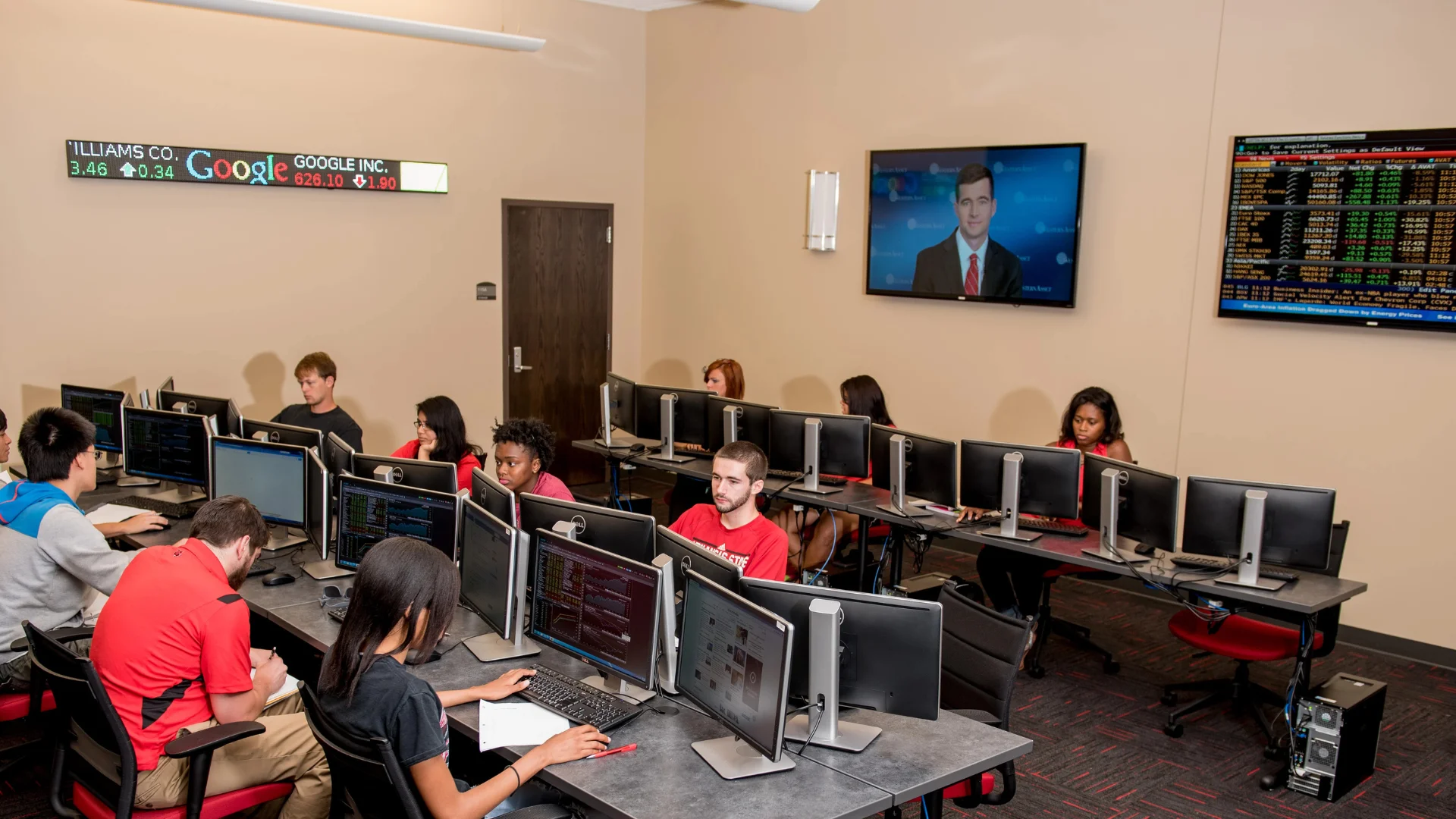Dawson Market room with various market boards displaying data and students sitting at computers working.
