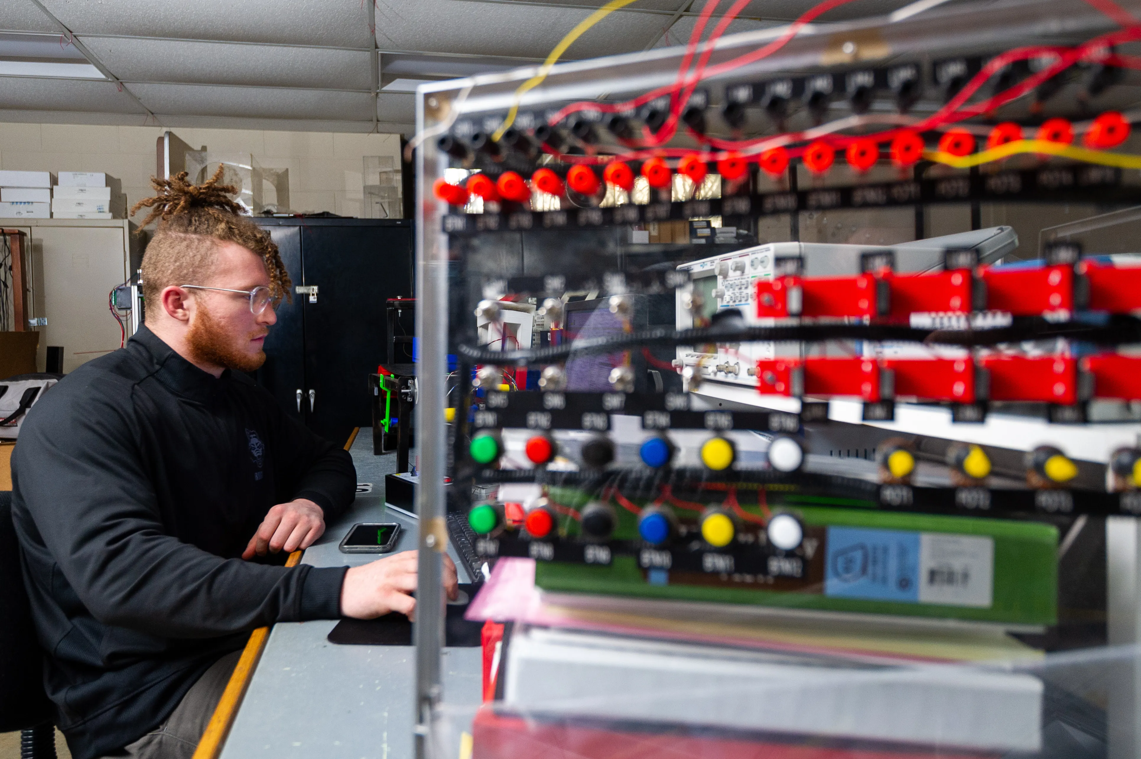 Electrical engineering student working on project with switches and knobs.