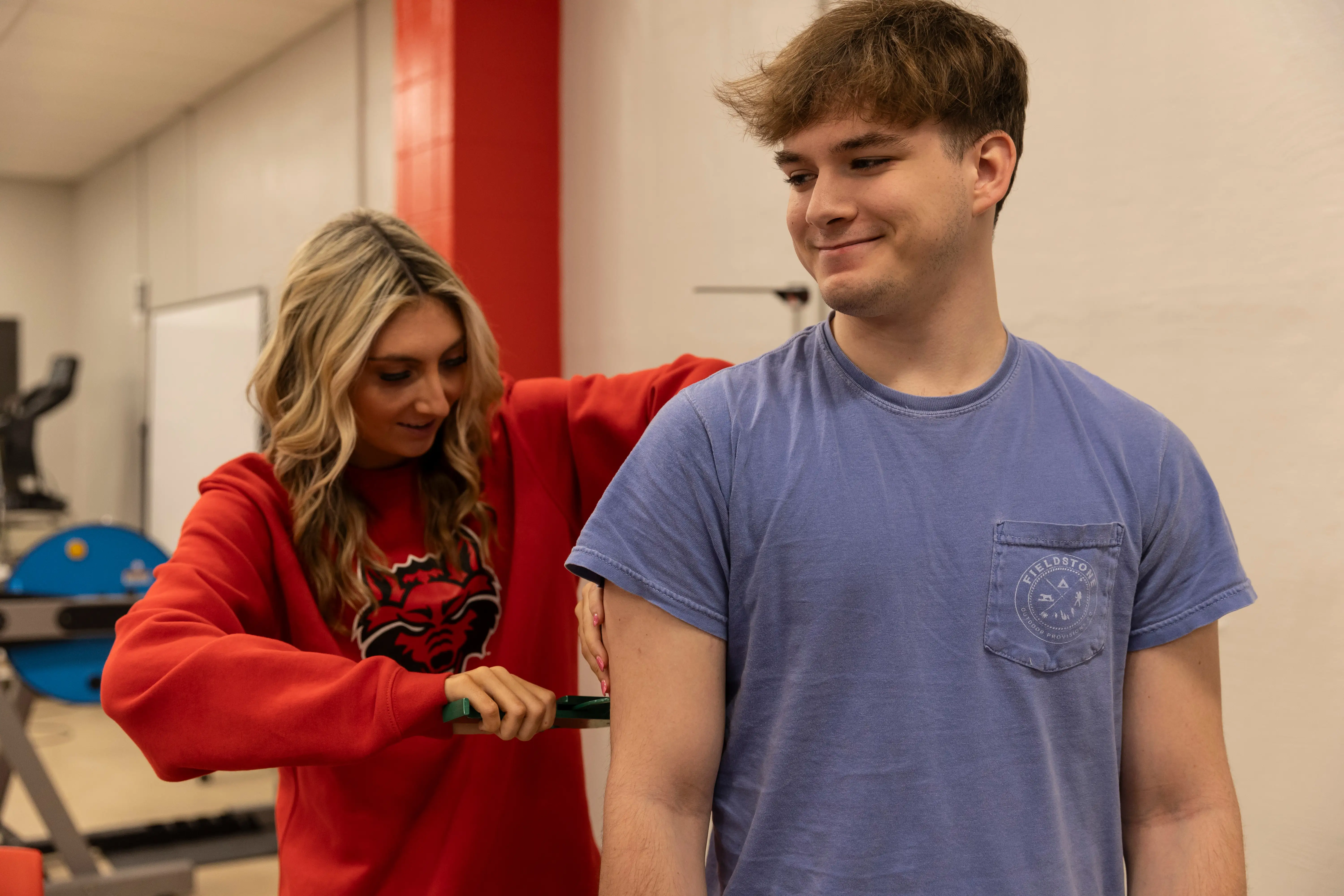A student measuring another student's bicep.