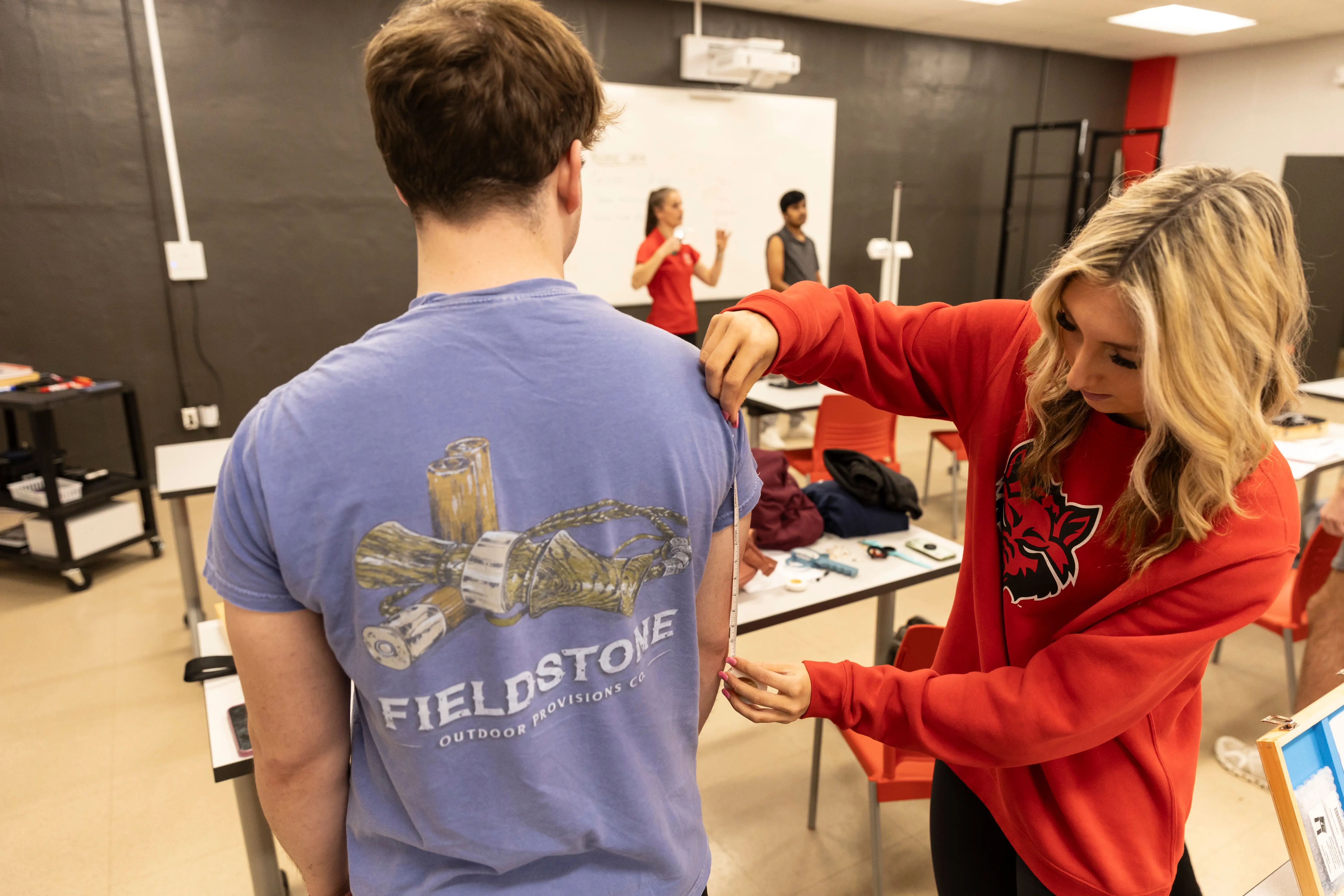 A student measuring another's arm.