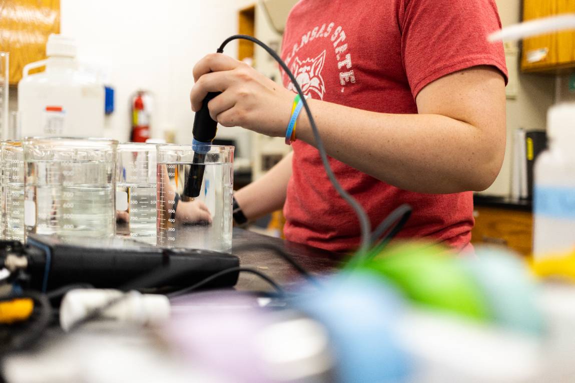 A student wearing a Red Wolves shirt performing ecotoxicology research in a lab.