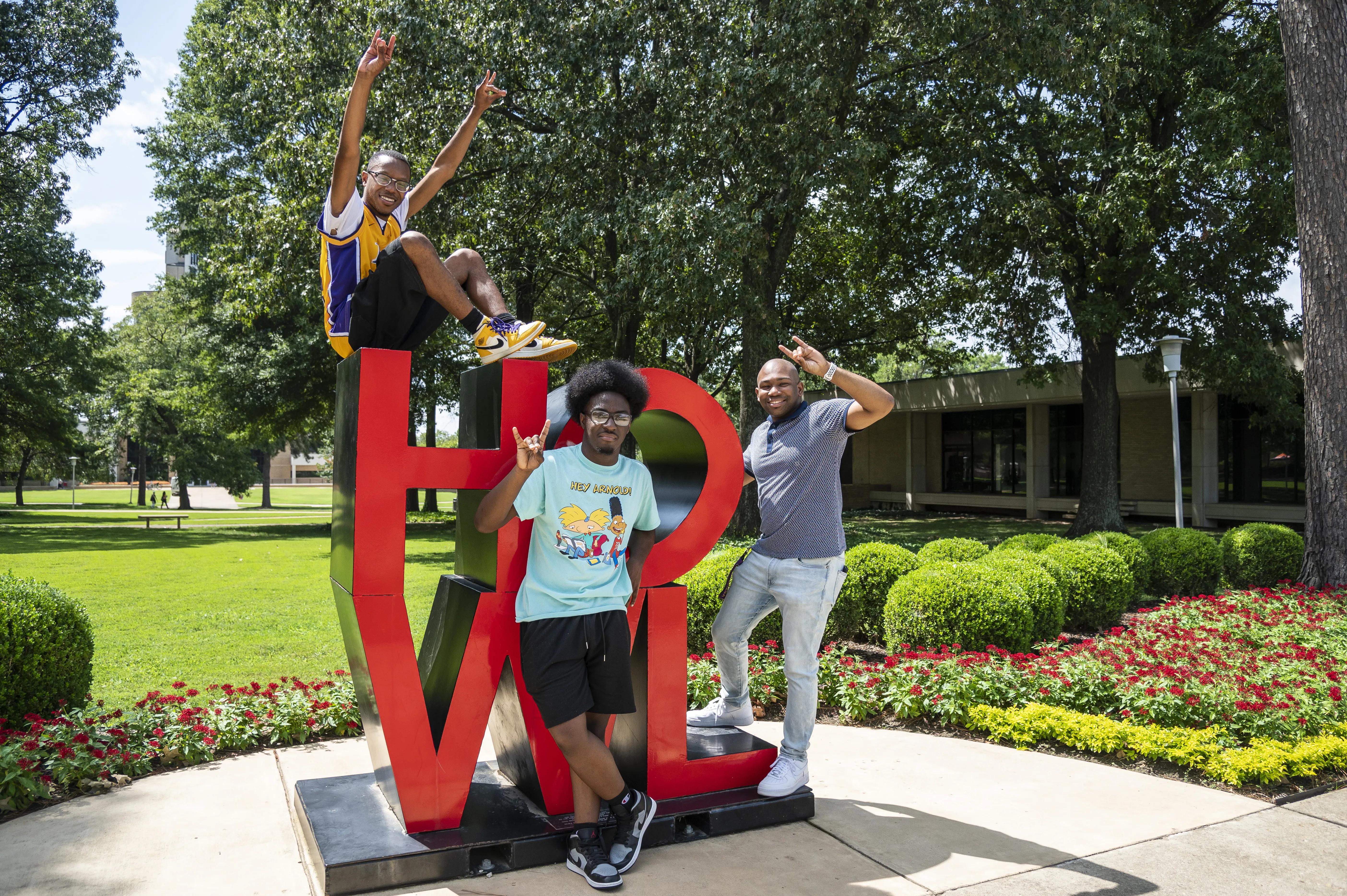 A-State student on laptop in red wolves shirt.