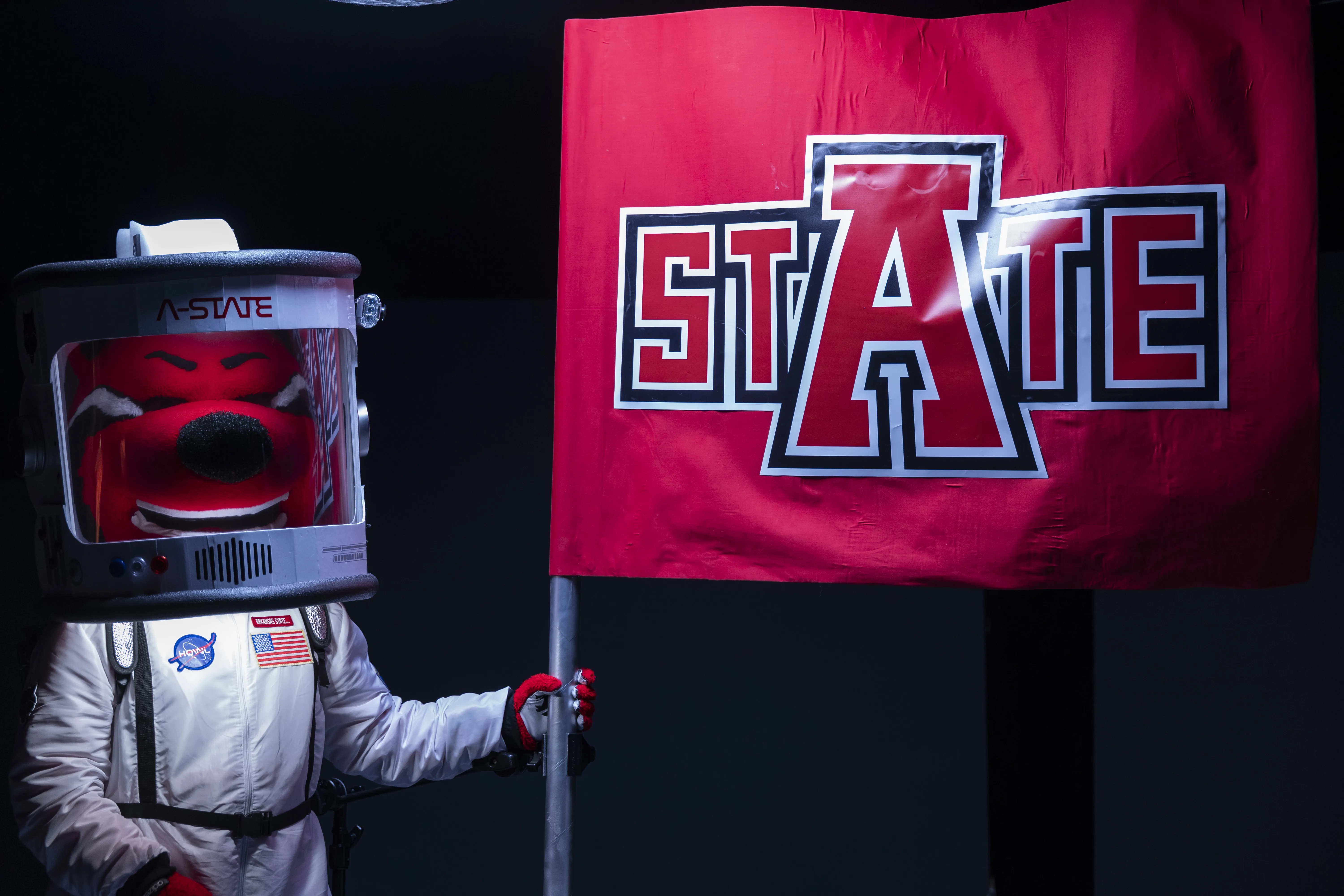 Howl in astronaut suit holding A-State flag