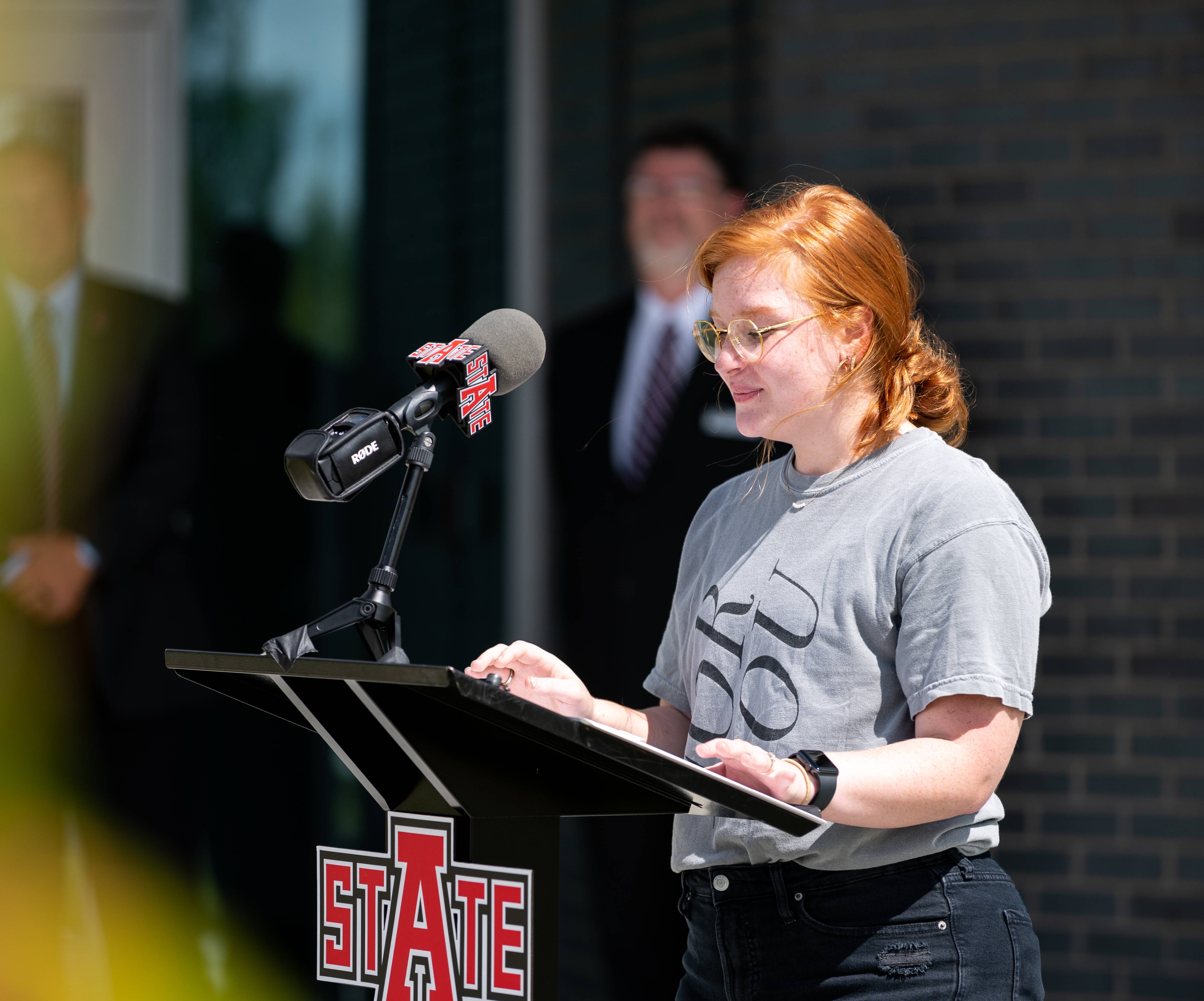 A student giving a public speech at a podium.