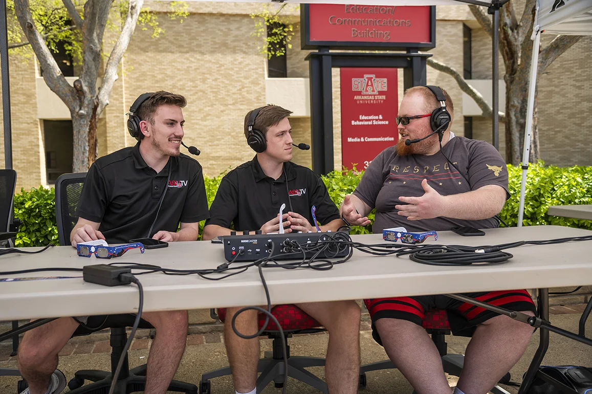 Three students discussing sports on the radio.