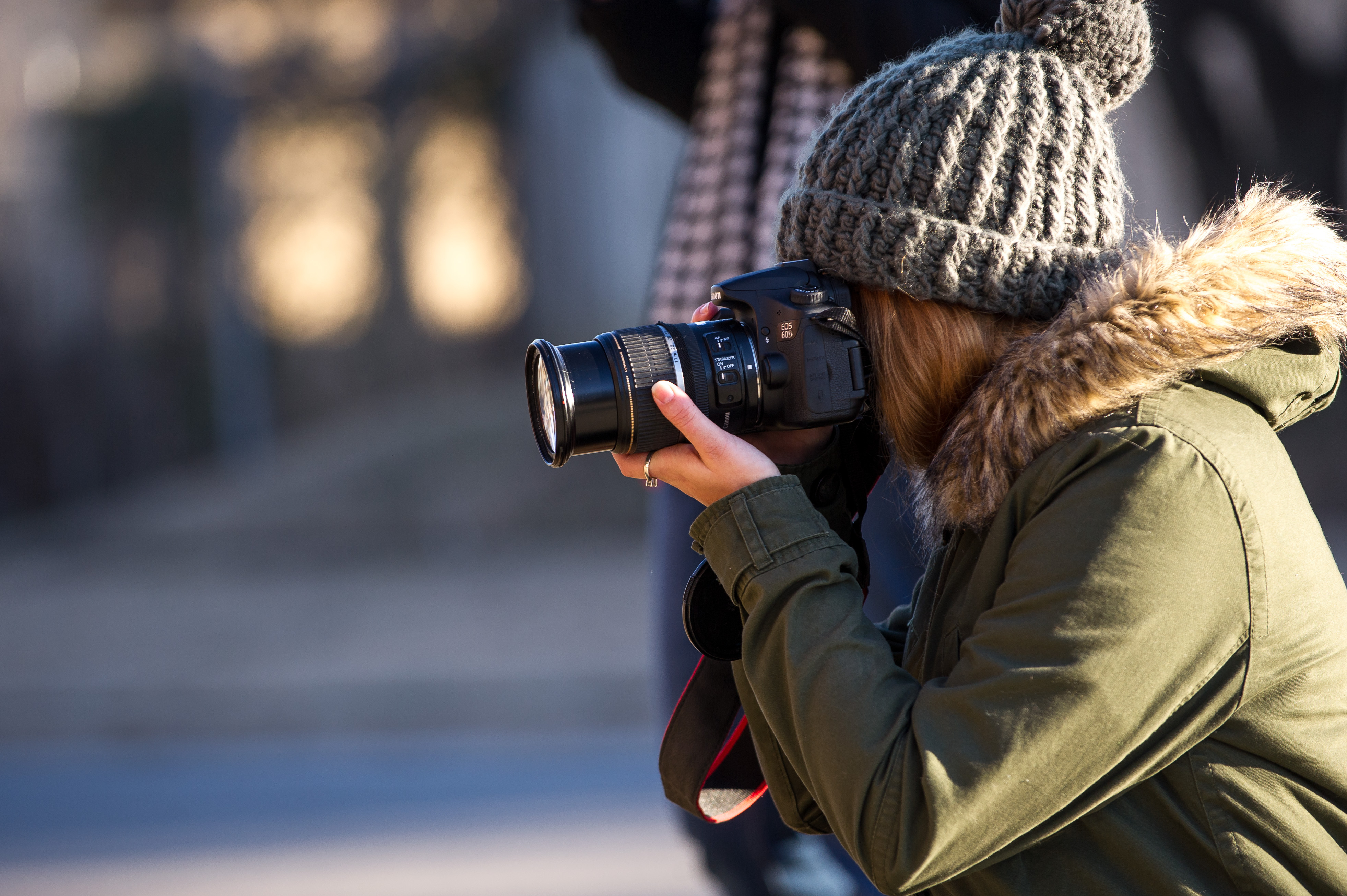 A photo of a woman holding a camera up to her eye and facing to the left.