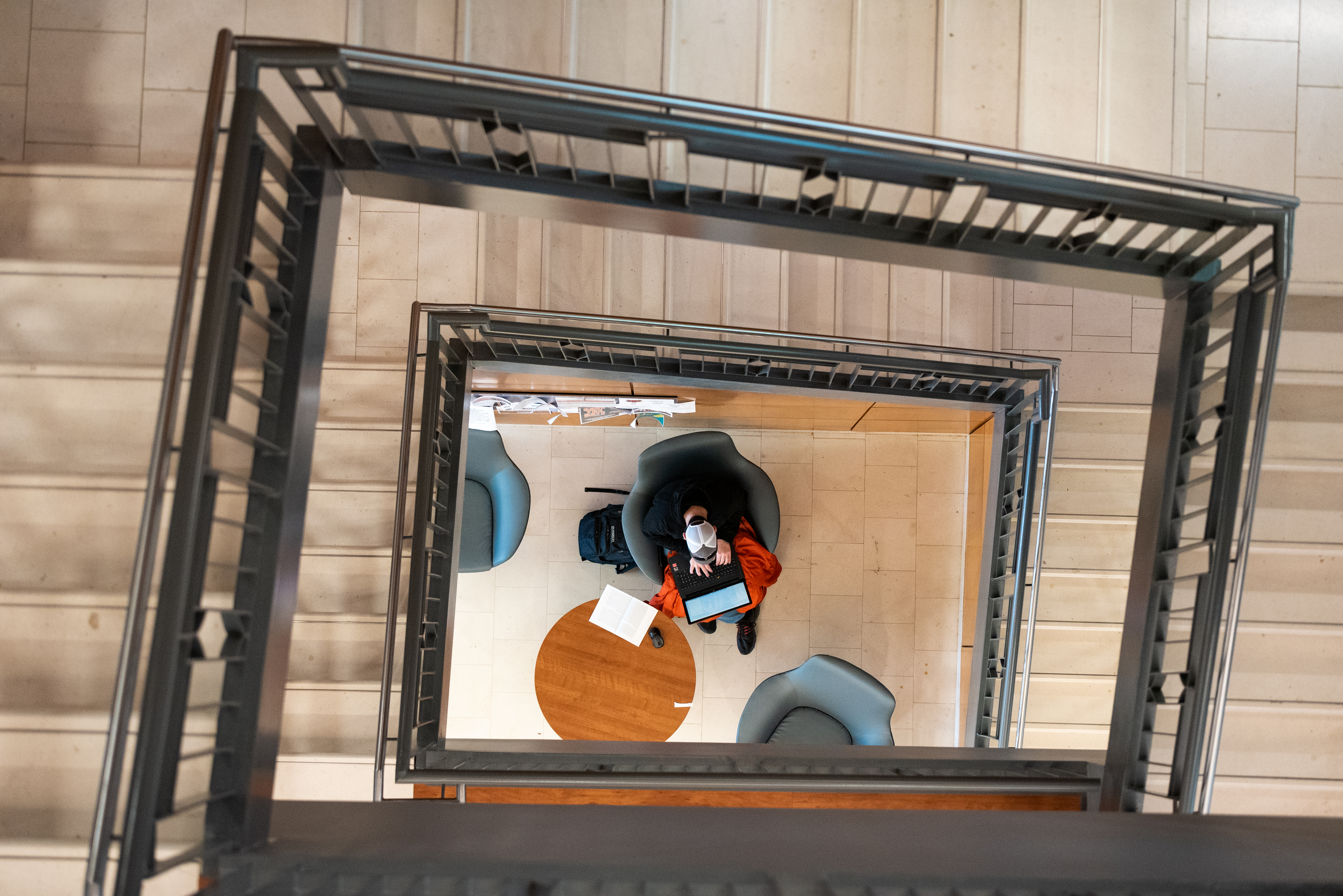 A top-down view of a student sitting at the bottom of a staircase