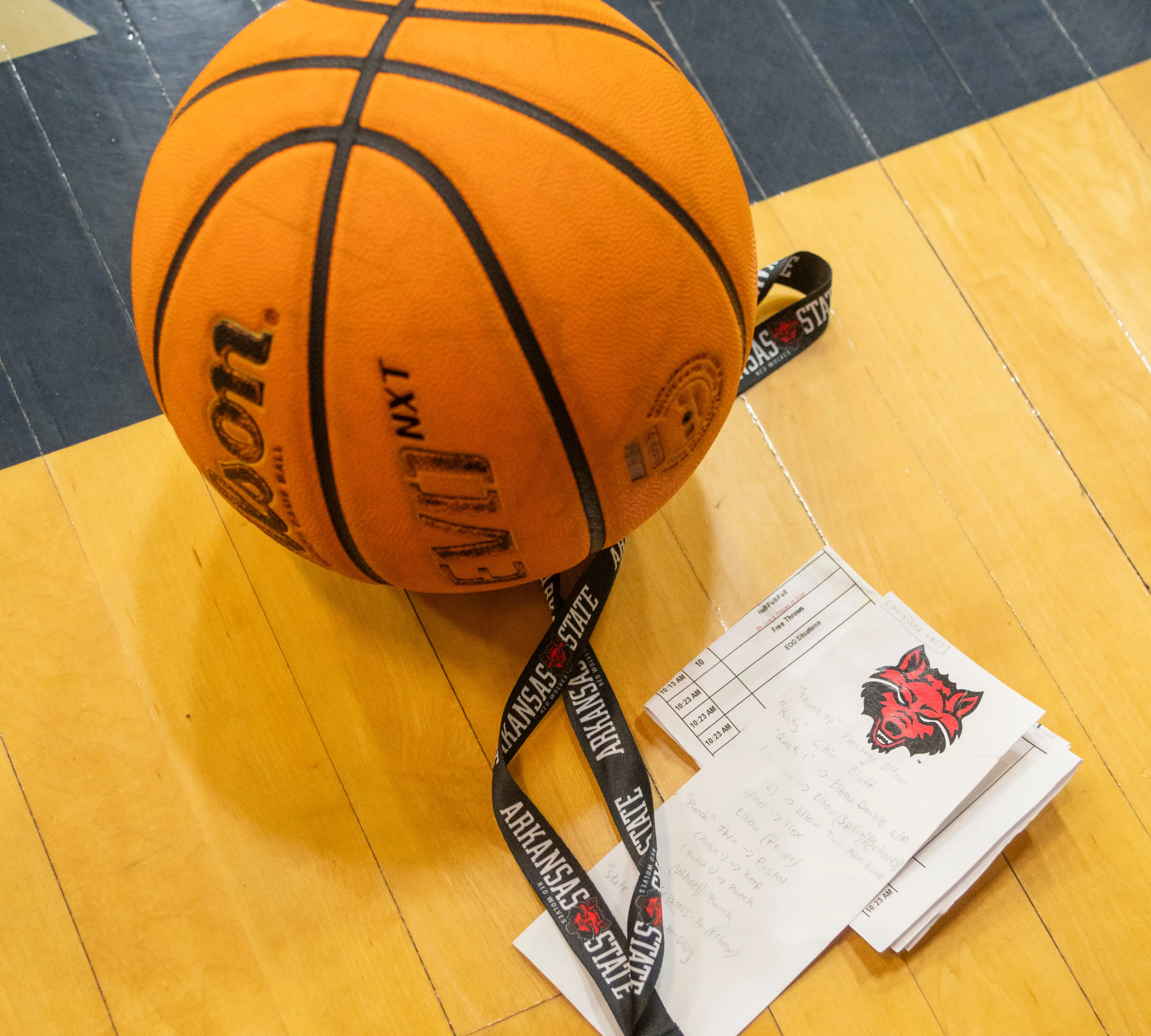 A basketball beside a lanyard and a flyer with the Red Wolf logo on it.