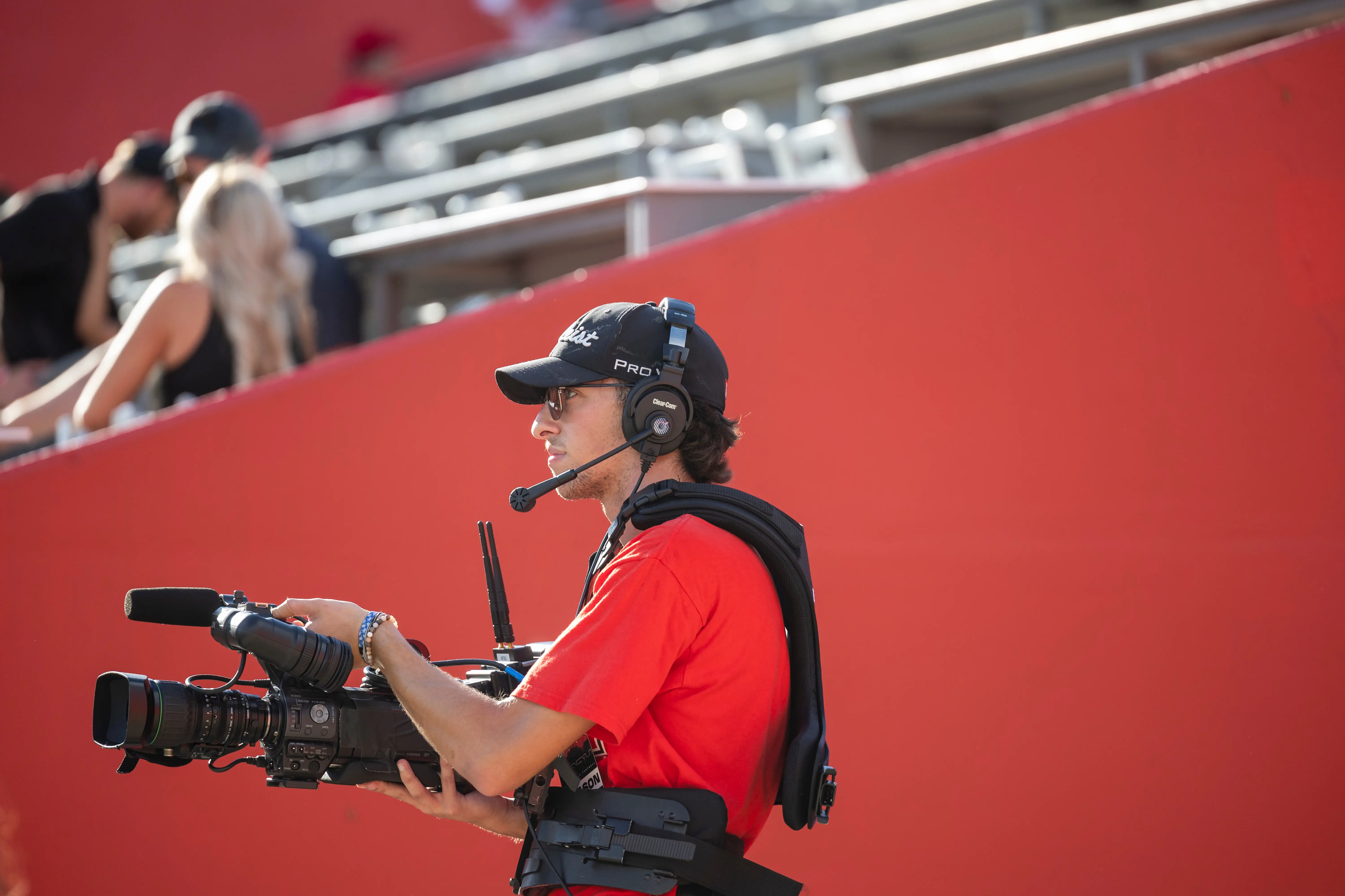 A student working a sideline camera during a sports game.