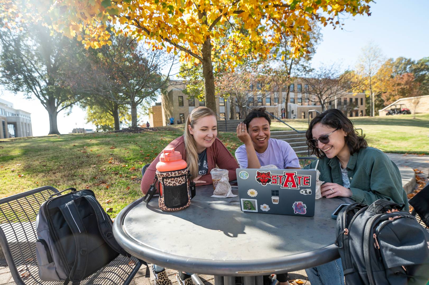 Students huddled around a laptop and smiling.