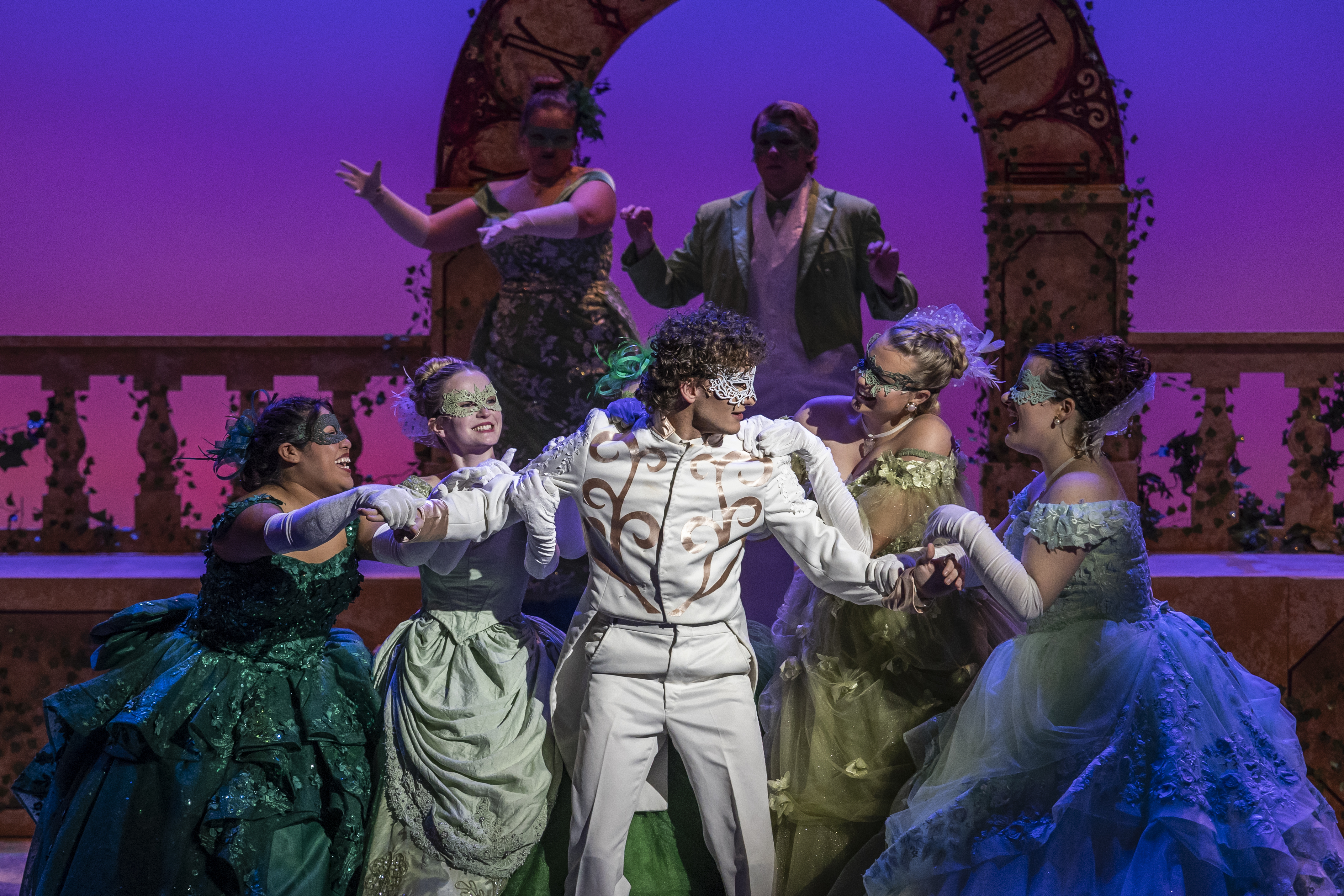 A photo of a group of actors performing in masquerade attire.