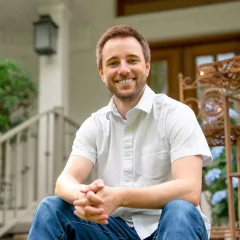 Trenton Hoggard sitting outside of house on steps on a sunny day.