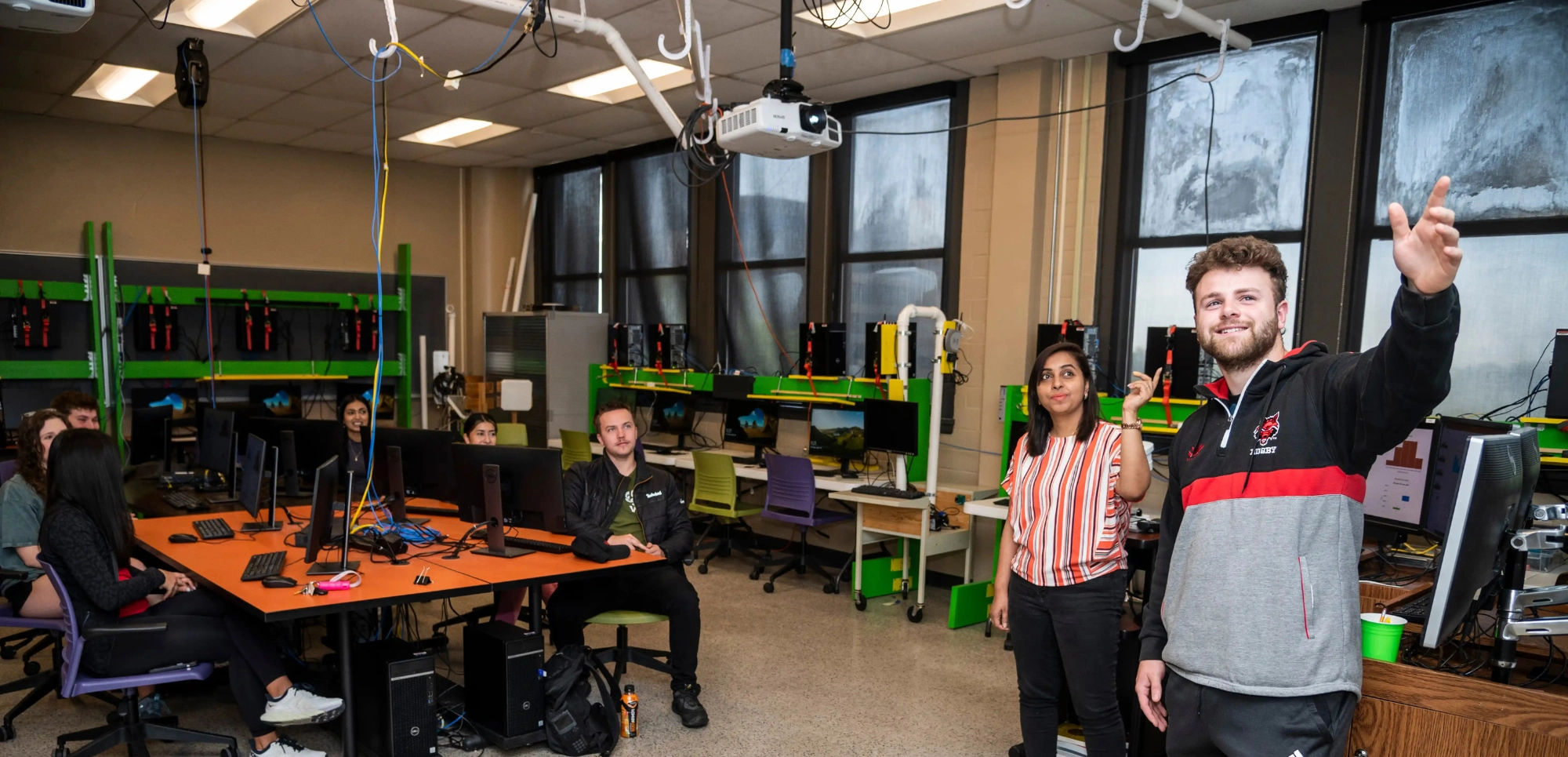 Student and professor at the front of class pointing at the AI and data lesson from the projector.