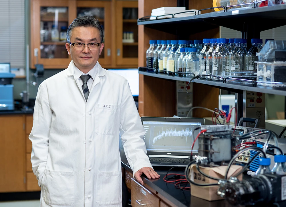 professor in white lab coat poses inside an ABI lab